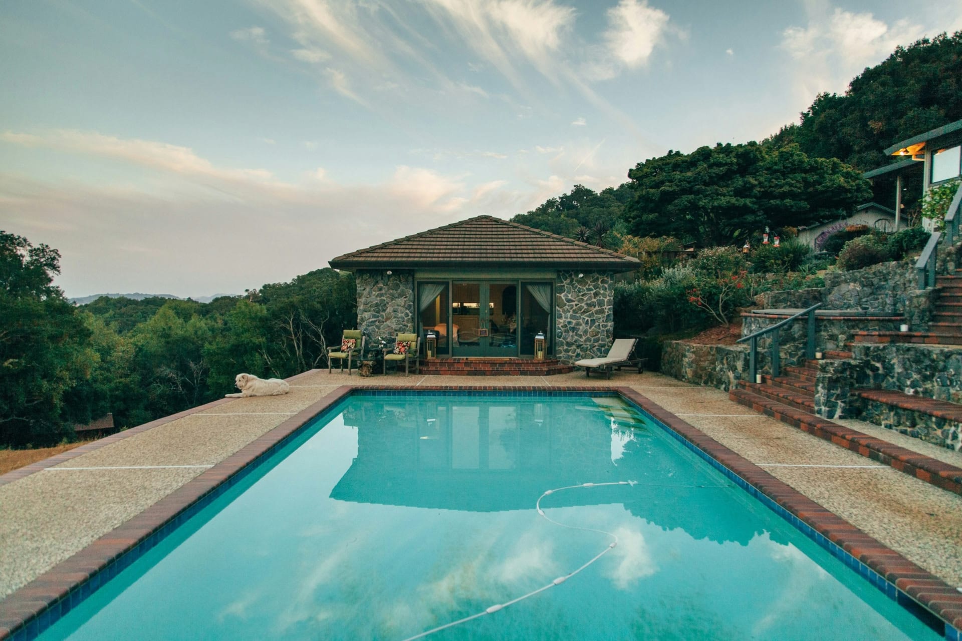 Piscine à débordement au revêtement sombre bordée d’une terrasse en bois